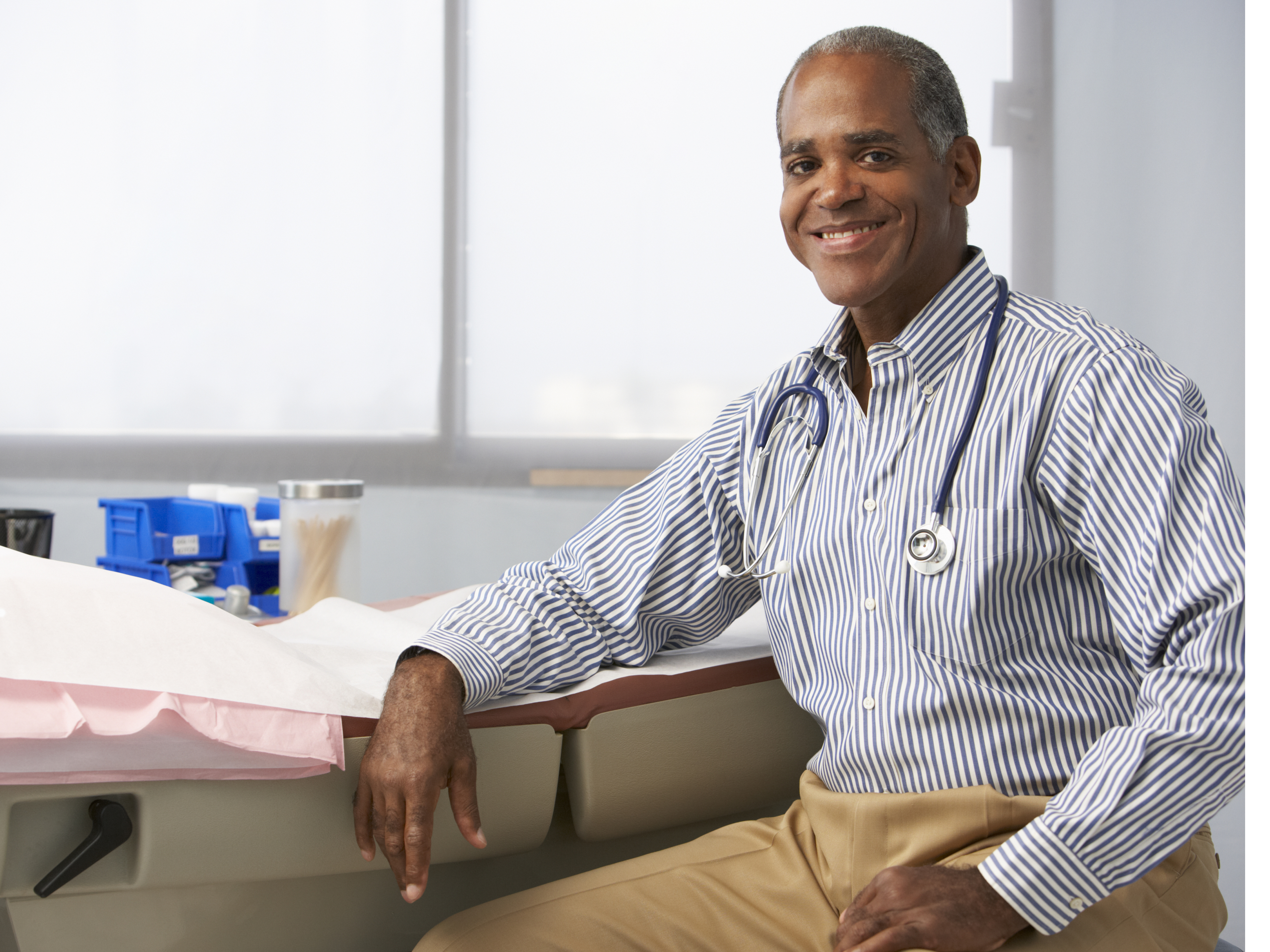 Male doctor smiling at the camera while seated.