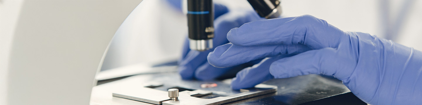 Researcher wearing gloves and using microscope