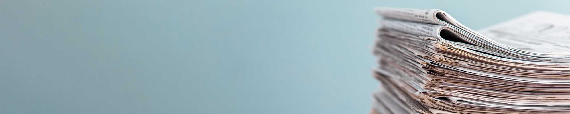 Stack of folded newspapers on a gradient blue background.
