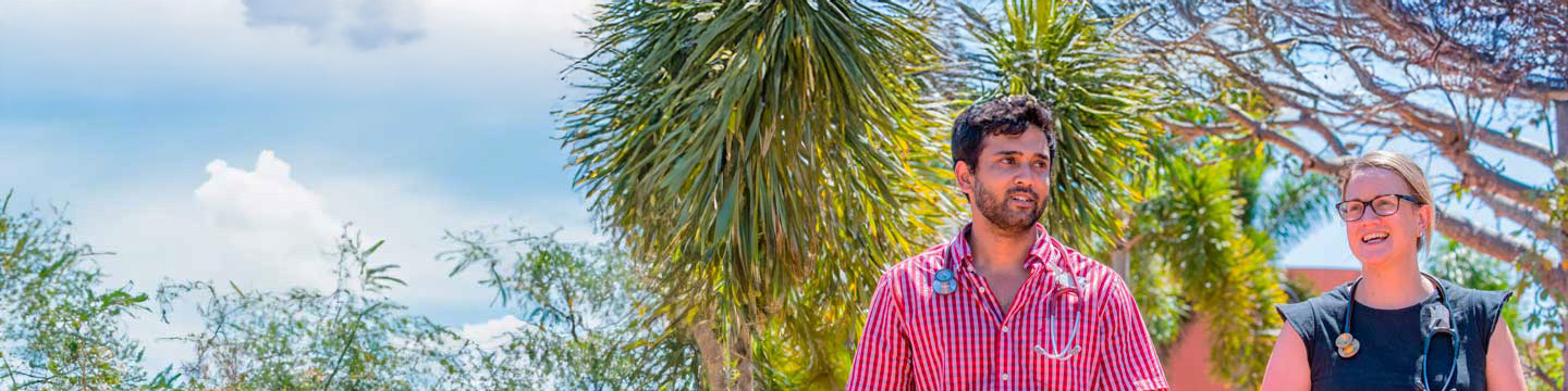 Two healthcare professionals walking outdoors, smiling, with stethoscopes around their necks.