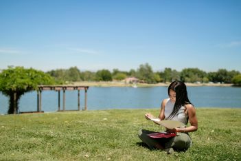 woman sitting crossed legged at the park reading notes