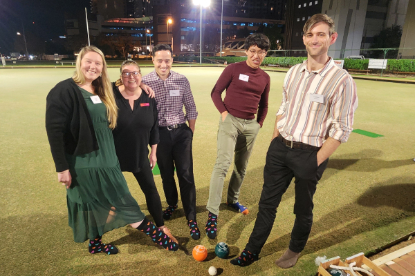 Five trainees showing off their colourful polka-dot socks in front of a lawn bowl green in Perth