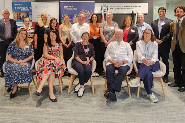 Group photo of people seated and standing indoors in front of banners for WA Country Health Service, RACP, and a strategic plan