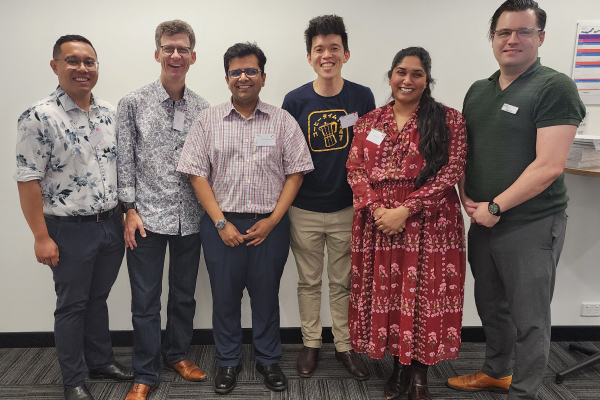 Six people standing indoors during the WA Trainees Day 2025, posing for a group photo against a light wall.