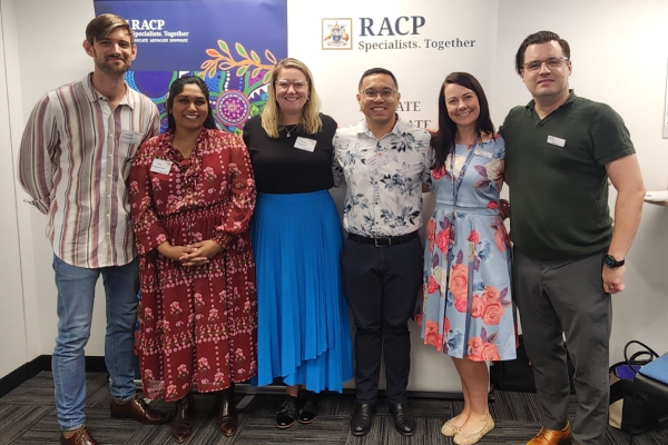 Six people standing indoors during the WA Trainees Day 2025, posing for a group photo against a light wall.