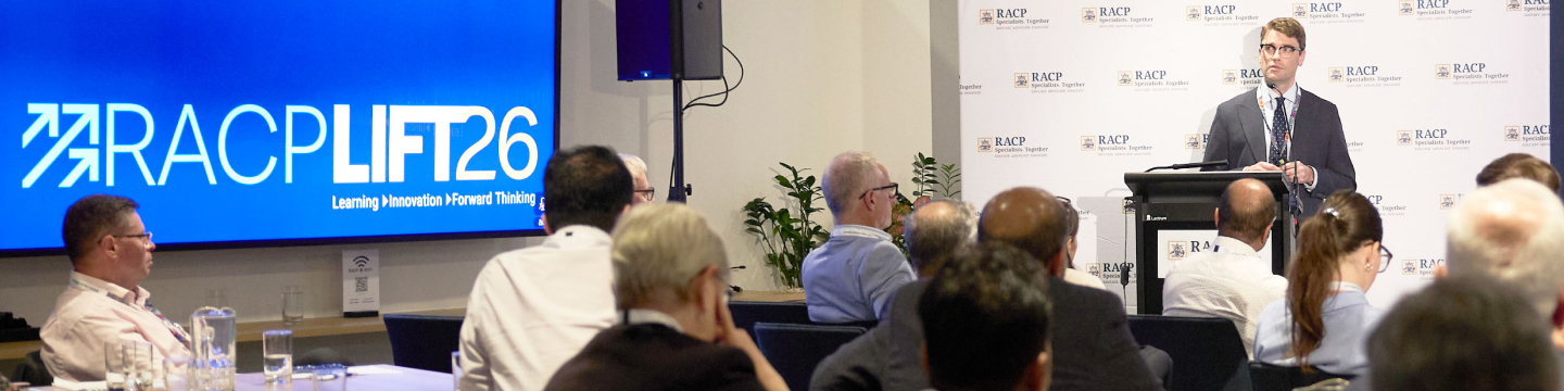 Speaker at podium addressing an audience at a RACP LIFT'26 conference, with event logo on a large screen behind
