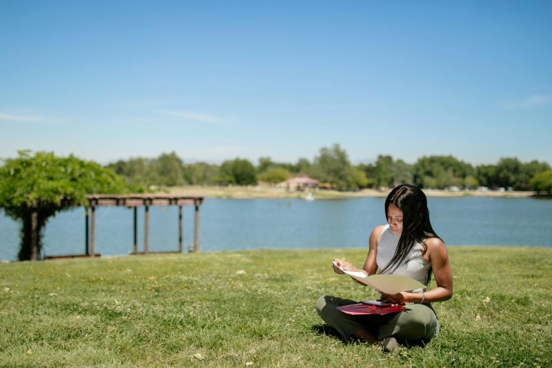 woman sitting on grass reviewing notes in folder