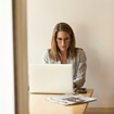 Working at laptop woman sitting at a table typing on a laptop