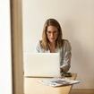 woman sitting at a table typing on a laptop