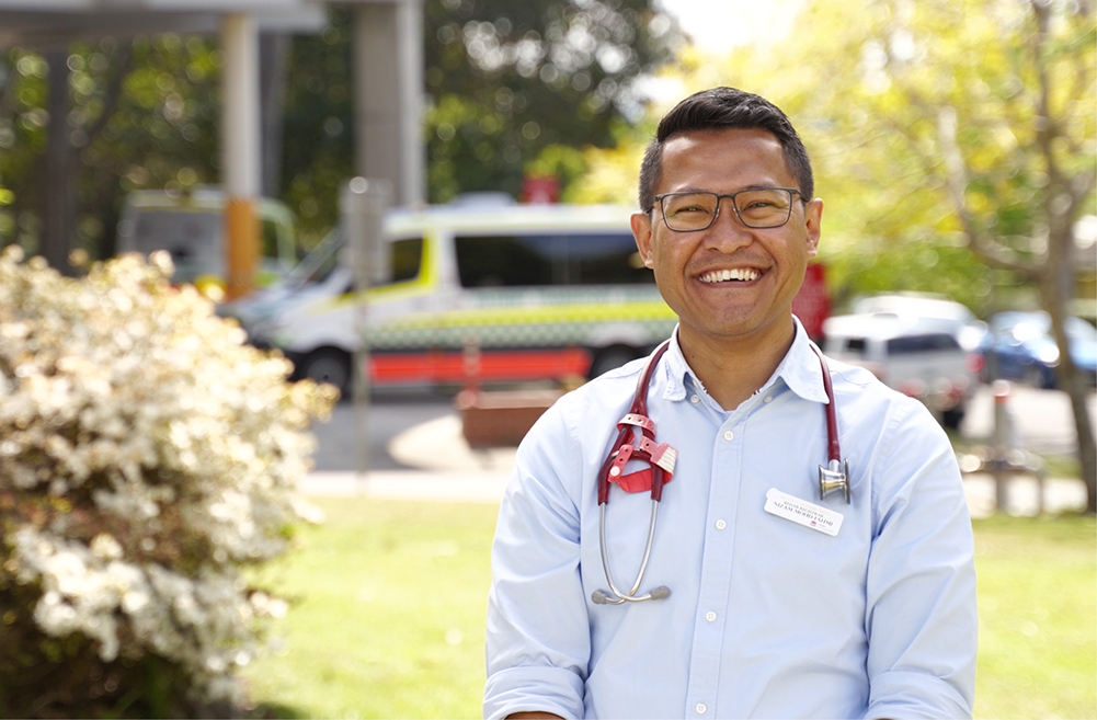 male physician outside a hospital smiling