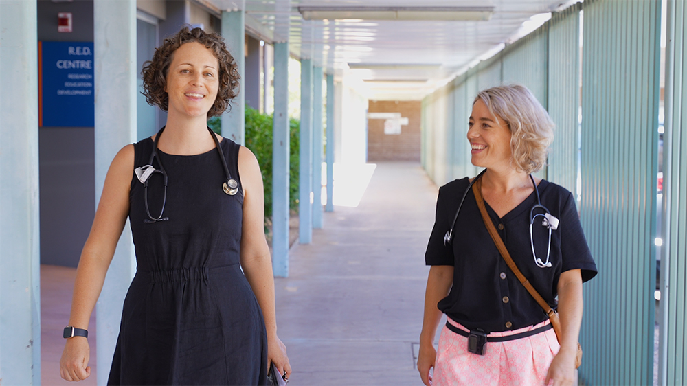 2 female physicians walking hospital corridor